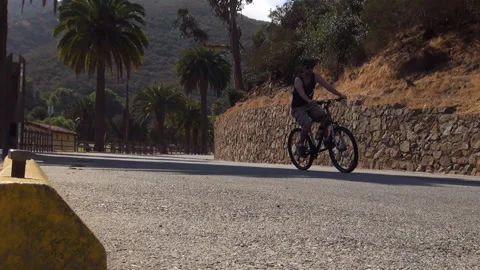 Bicyclist pedals down an empty the road on Catalina Island, CA Stock Footage 137808863