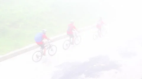 Bicyclists riding through thick bright fog Stock Footage 37160991