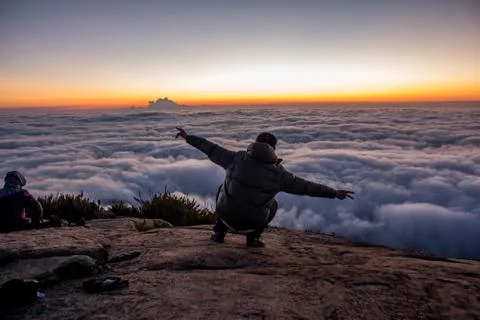 Big achievement watching sunrises on top of a mountain between the clouds Stock Photos
