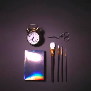 Big alarm clock, brush set, scissors and holographic notepad Stock Photos