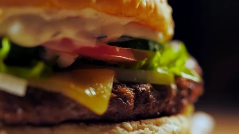 Big appetizing burger with meat cutlet, onion, vegetables, melted cheese Stock Footage 98426096