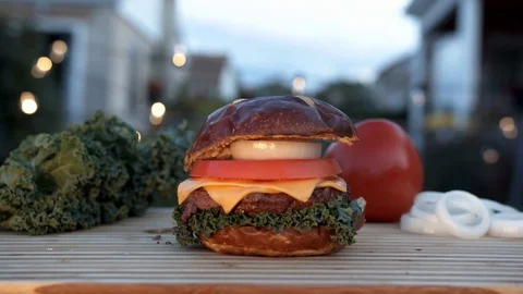 Big appetizing burger with meat cutlet, onion, vegetables, melted cheese and Stock Footage 116917615