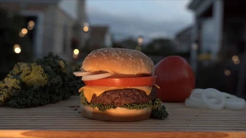 Big appetizing burger with meat cutlet, onion, vegetables, melted cheese and Stock Footage 116918364
