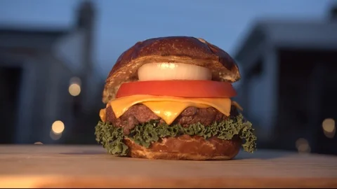 Big appetizing burger with meat cutlet, onion, vegetables, melted cheese and Stock Footage 116919076