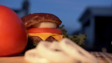 Big appetizing burger with meat cutlet, onion, vegetables, melted cheese and Stock Footage 116919241