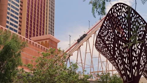 The Big Apple Roller Coaster in Las Vegas climbing with riders on a sunny Stock Footage 280638597