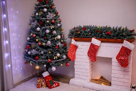 Big artificial New Year tree and home decorated in the evening. Gift boxes an Stock Photos