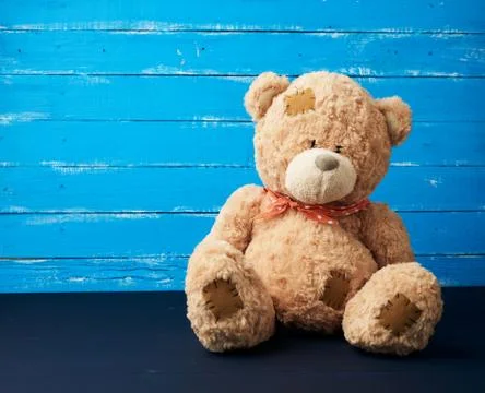 Big beige teddy bear sitting on a blue wooden background Foto stock