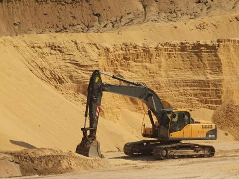 Big black orange digger in open sand mine is waiting for new shift. Stock Photos