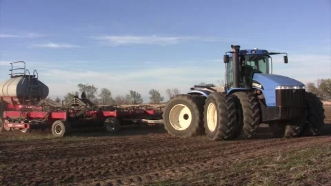 Big blue tractor Spring disc &amp; nitrogen trailers turns close then away fr cam Stock Footage 270237285
