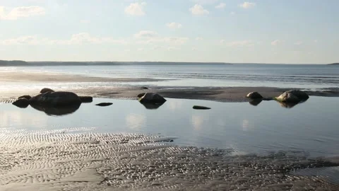 Big boulder rocks peaking out of the water on a sea bed on the sandy beach Stock-Footage 162272235
