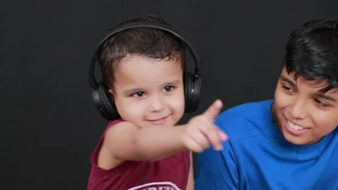 Big boy helping small boy to wear a headd phone in black background Stock Footage 160544067