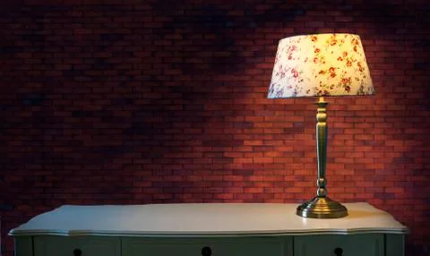Big brick wall and light lamp on white table Stock-Fotos