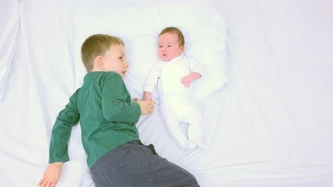 Big brother looking curious and touching newborn, child with new role, concern Stock Footage