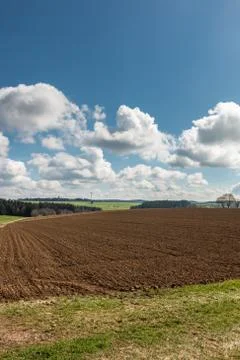 Big brown fields of fertile soil, green forest and wind power in the backgrou Stock-Fotos