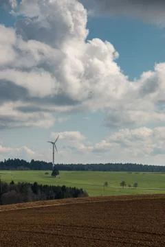 Big brown fields of fertile soil, green forest and wind power in the backgrou Photos