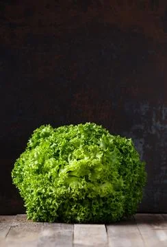 Big bunch of fresh lettuce leaves on a wooden table and dark background, co.. Stock Photos