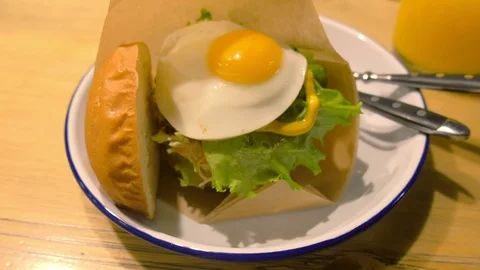 Big Burger with egg and fresh vegetables served on plate with fork and knife. Stock Footage 117621652