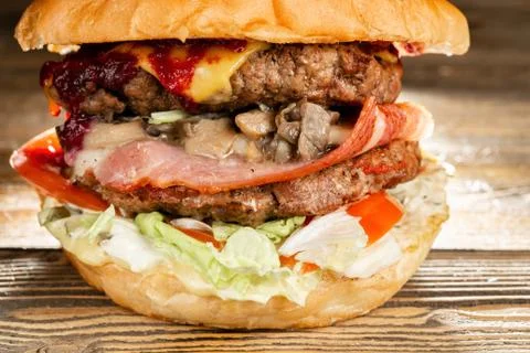 A big burger with two beef cutlets, cooked on charcoal. Lunch on a wooden Stock Photos