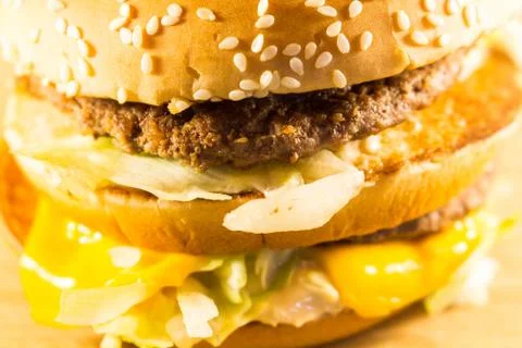 Big burger with two cutlets, cheese and salad. Side view Фото