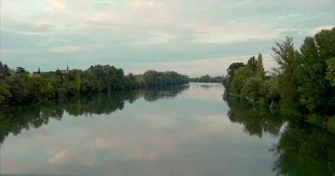 Big calm river reflecting sky and church behind the trees Stock Footage 81358166