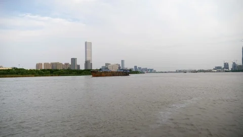 Big Cargo Ship on a River with Buildings in the Background on a Cloudy Day 4k Stock Footage 123049648