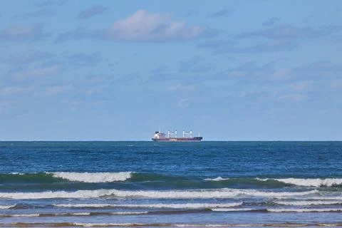 A big cargo ship sails along the coast Stock Photos