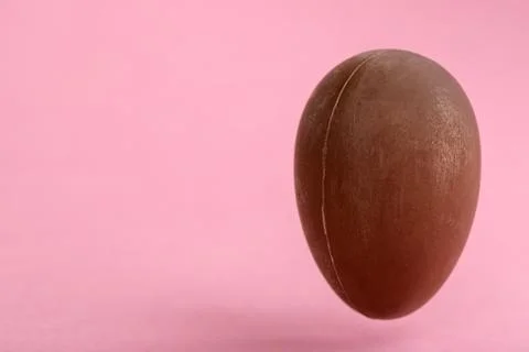 Big chocolate Easter egg on pink background with copy space funny creative co Stock Photos