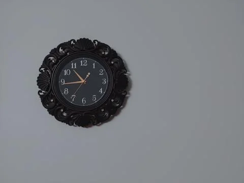 Big circle shape brown wall clock with yellow second hand hanging on the wall Stock Photos