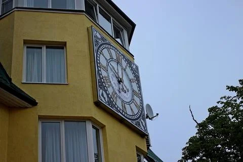 Big clock high on the building between the windows in Zelenogradsk Stock Photos