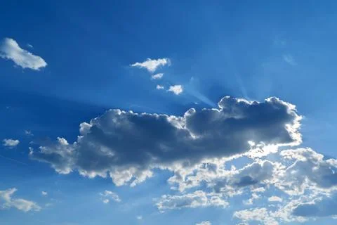 A big cloud covered the sun. Through the clouds shining rays of the sun. Stock Photos