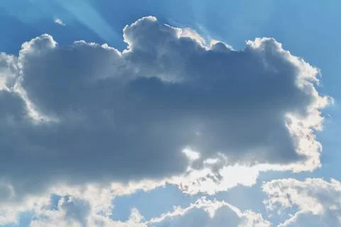A big cloud covered the sun. Through the clouds shining rays of the sun. Stock Photos