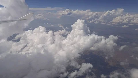 Big clouds and airplane wing in blue sky from window of aircraft Video stock 76674079