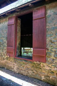 Big colonial wagon seen through open stone barn window with red wooden shutters Foto stock