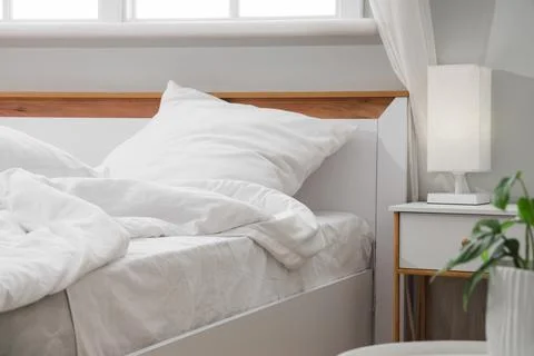 Big comfortable bed with white bedding in hotel room Stock Photos