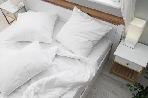 Big comfortable bed with white bedding in hotel room Stock Photos