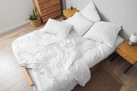 Big comfortable bed with white bedding in hotel room Stock Photos