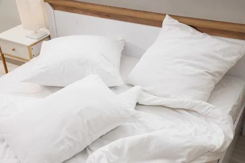 Big comfortable bed with white bedding in hotel room Stock Photos