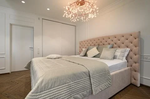 Big comfortable double bed in elegant classic bedroom Stock Photos