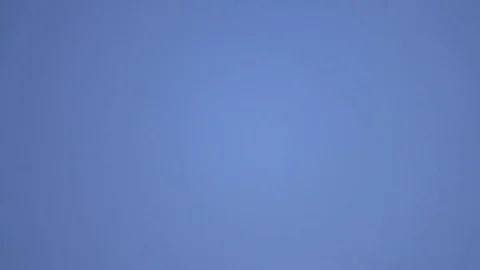 Big commercial airliner crosses the frame leaving contrail in blue sky Stock Footage