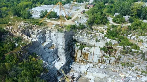 Big crane and a camera hit him in close-up in an open granite quarry at summer Stock Footage 113016556