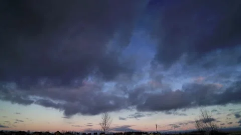 Big dark clouds lit by the rays of the sunset sun, are floating in the blue sky 動画素材 143157901