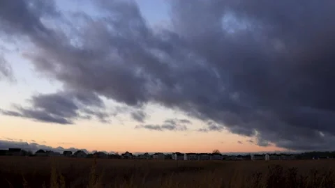 Big dark clouds lit by the rays of the sunset sun, are floating in the blue sky Video stock 143157922