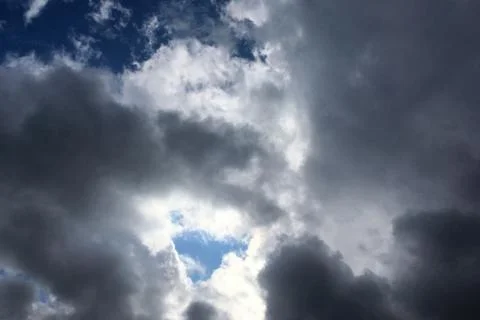 Big dark dramatic fluffy clouds in the blue sky on sunny light. Abstract natu Stock Photos