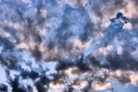 Big dark dramatic fluffy clouds in the blue sky on sunny light. Abstract natu Stock Photos