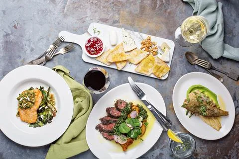 Big dinner table overhead view with steak and fish Stock Photos
