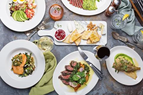 Big dinner table overhead view with steak and fish Stock Photos