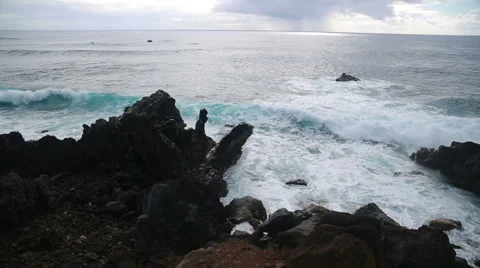 Big dramatic waves roll and crash onto the volcanic rocks Stock Footage 64257896