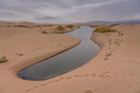 Big dune and the sand texture with the river cutting through at foreground,.. Stock Photos