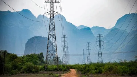 Big electrical pole next to a dirt path with mountains in the background, T.. Stock Photos